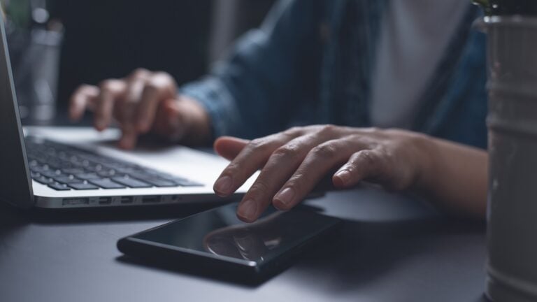 woman working on laptop computer and using mobile phone at night from home office, overtime working